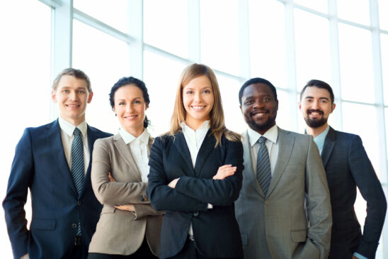 Group of business partners looking at camera with smiles, pretty leader in front